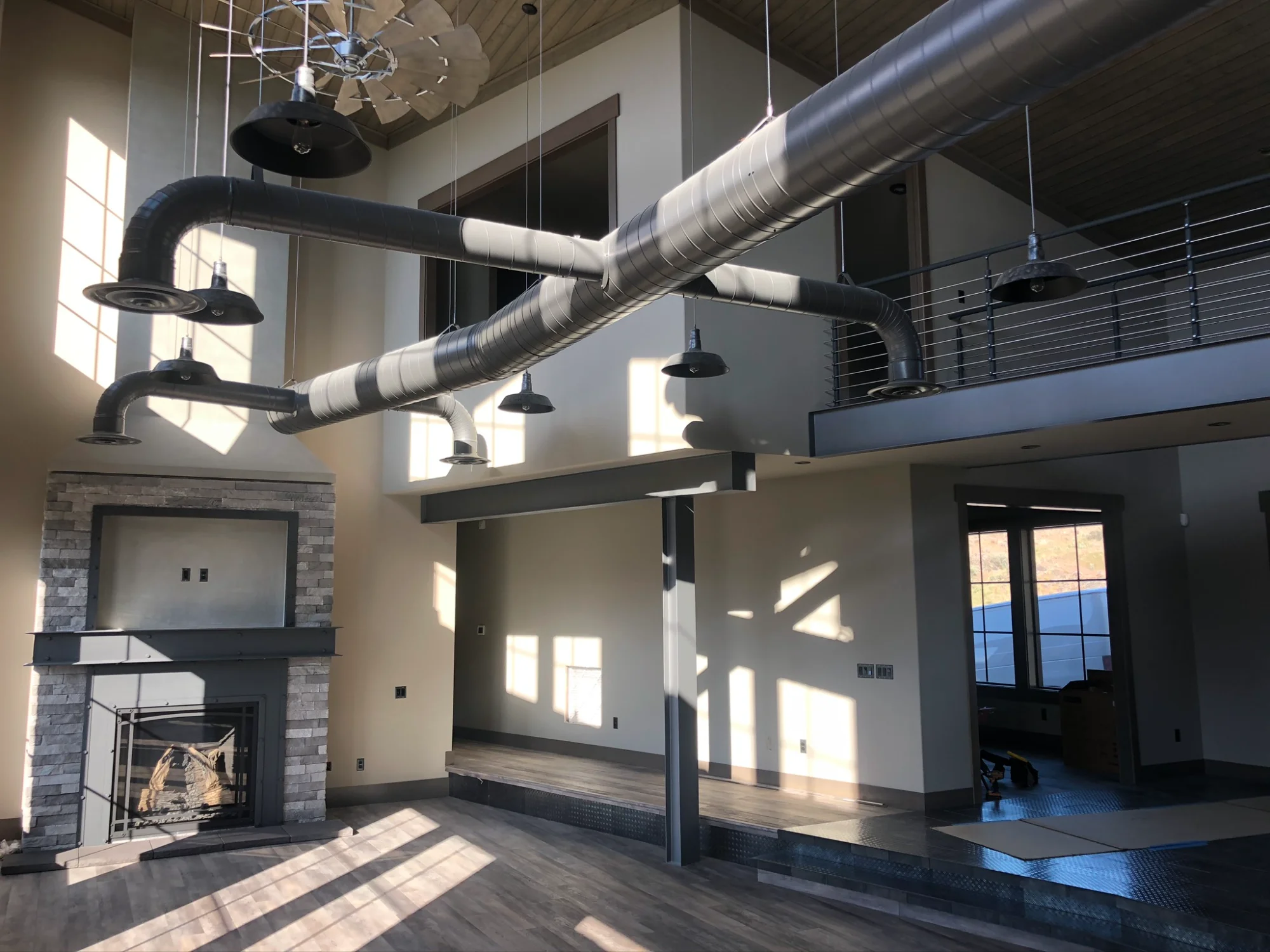 Custom exposed spiral ductwork in modern great room with stone fireplace