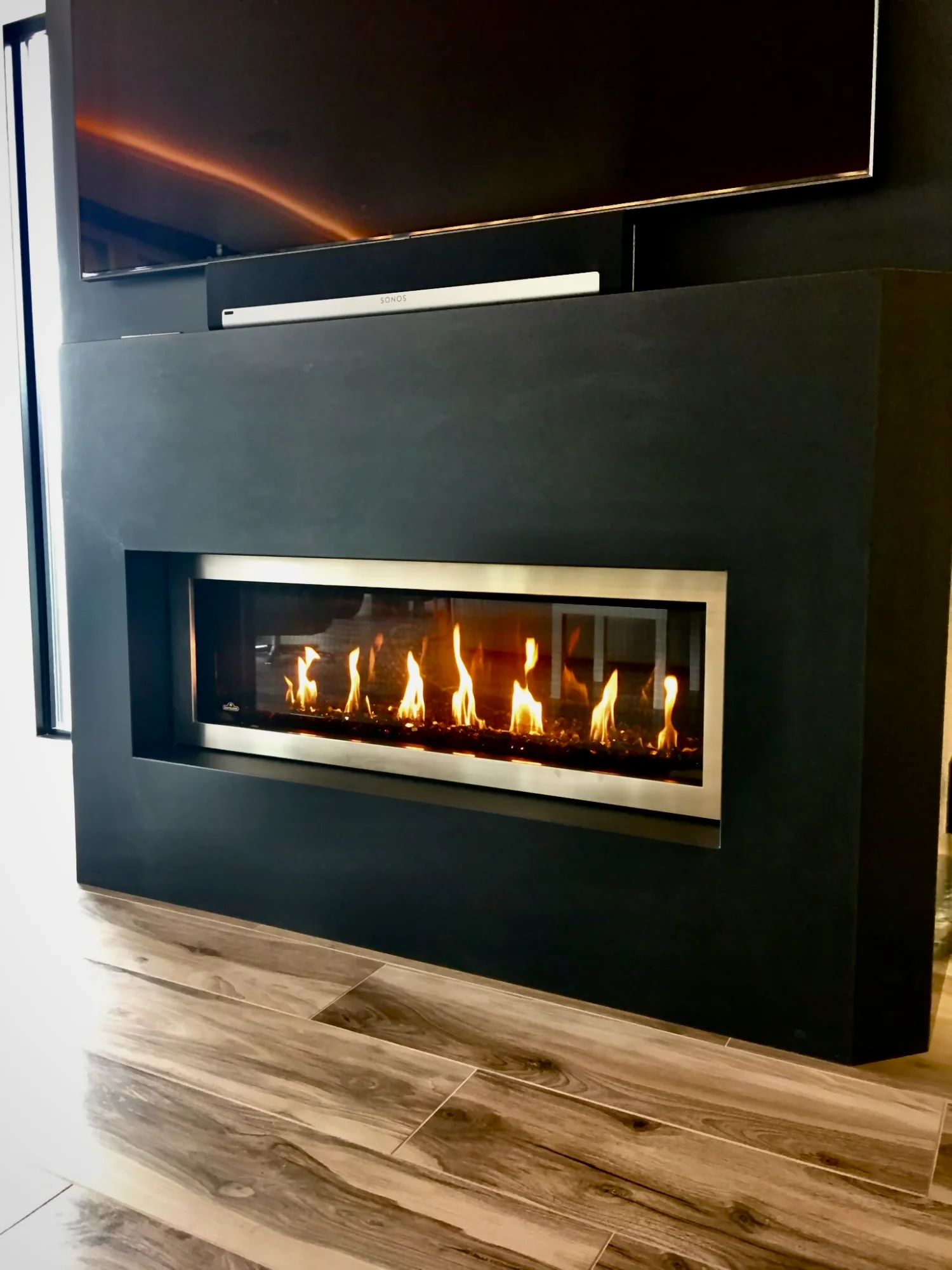 Modern linear gas fireplace with black surround and TV mount