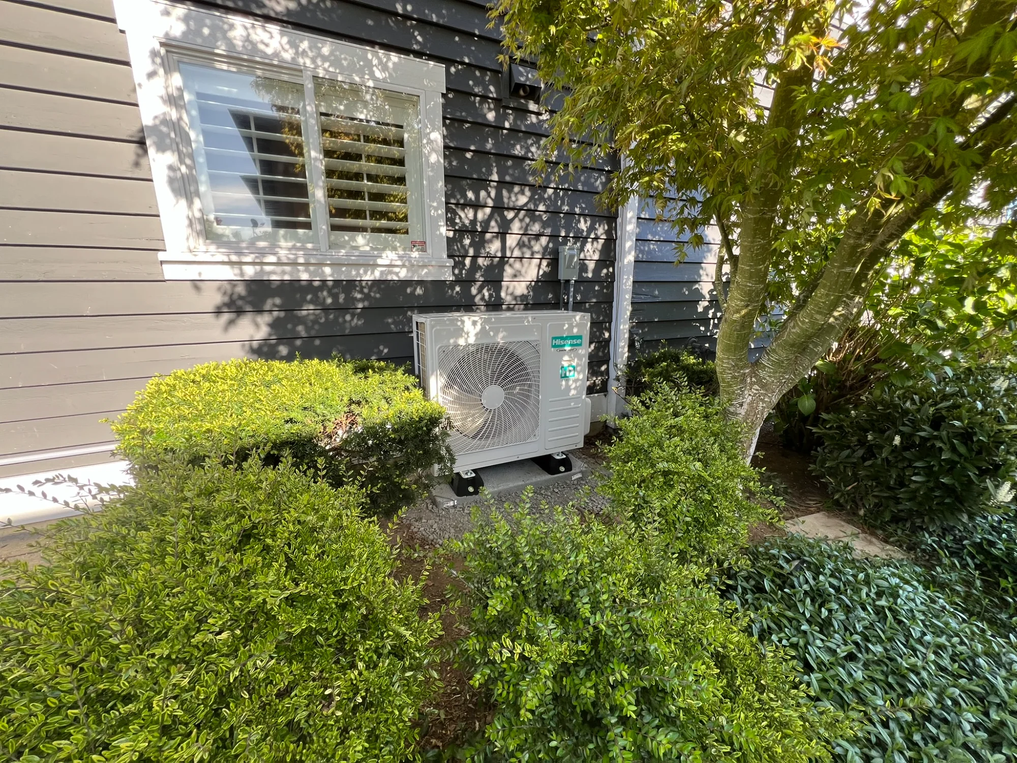 Residential heat pump installed beside a Pacific Northwest home